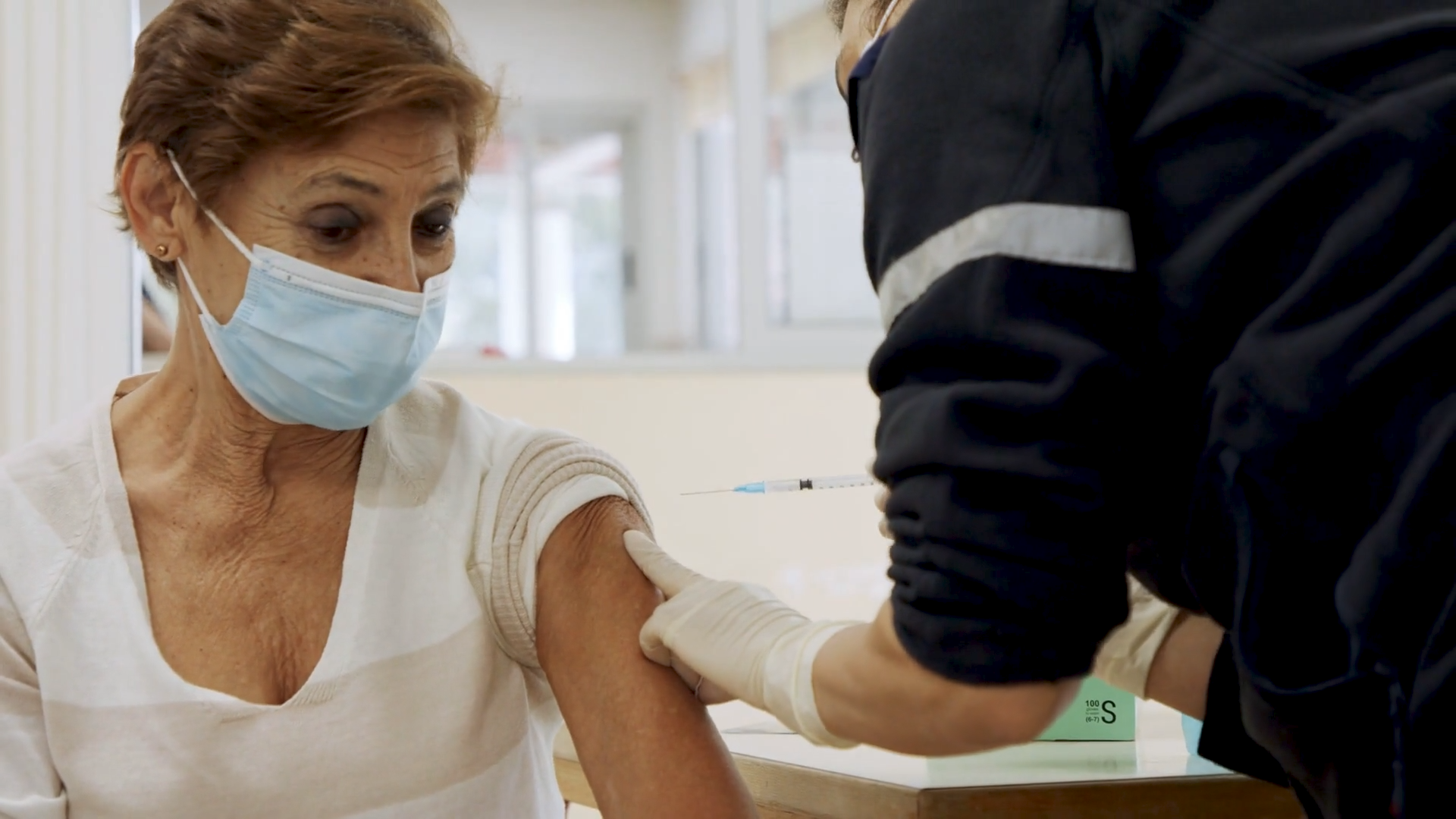 Photo of woman in mask getting a shot. 